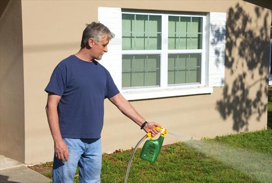 Man spraying liquid fertilizer on lawn
